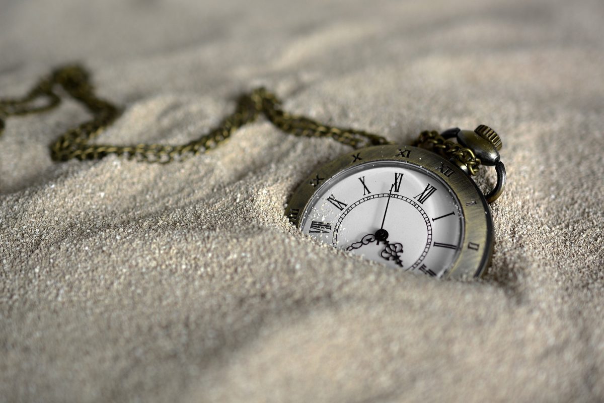 Reloj enterrado en la arena, simbolizando el paso del tiempo.